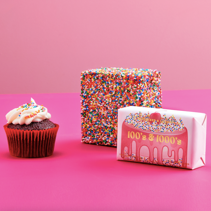 Cupcake, box of candy, and pink packaging with '100's & 1000's' branding on a pink background