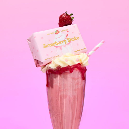 Strawberry milkshake with a strawberry on top against a pink background